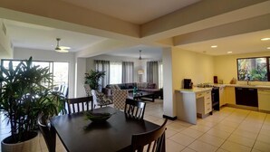 A spacious living area with a dining table, sofa, and kitchen. - Hilltop condo with beautiful ocean view! (Tarcoles)