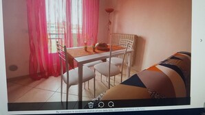 A room with a dining table and chairs, a sofa, and a window with red curtains. - TWO-ROOM APARTMENT PIOMBINO MARE 50 MT - 4 PANORAMIC BEDS (Piombino)