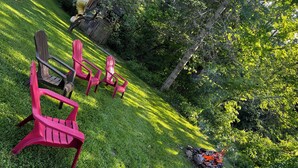 A grassy outdoor area with red chairs and a fire pit. - Cozy 3 bedroom 2 bath home close to hiking, biking, and Stowe! (Hyde Park)