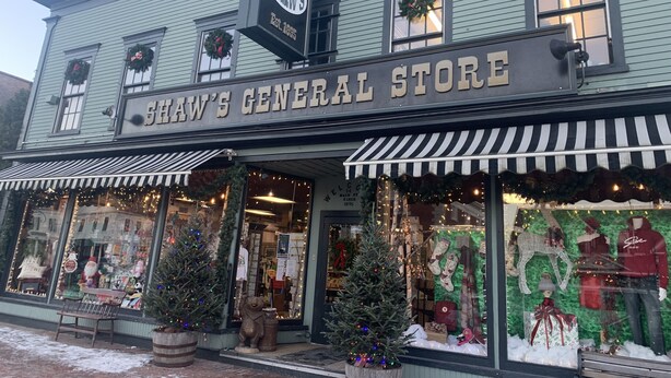 A building with a sign reading "H.E. Shaw Co. Shaw's General Store" and a Christmas display with a Christmas tree and stockings. - Cozy 3 bedroom 2 bath home close to hiking, biking, and Stowe! (Hyde Park)