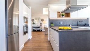 A modern kitchen with stainless steel appliances, a central island, and a view into the dining area. - Genteel Home Elcano Terrace (Malaga)