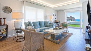 A modern living room with a sofa, coffee table, and wicker chair. There is a bookshelf and a TV on the right side. - Genteel Home Elcano Terrace (Malaga)