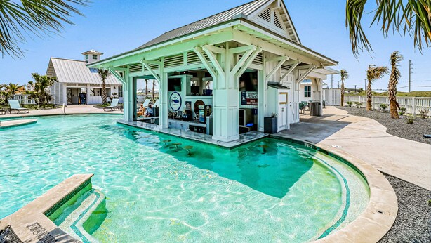 A pool area with a covered bar and lounge chairs. - Dreamy beach escape on the 9th hole with balcony and WiFi - steps to pool (Port Aransas)