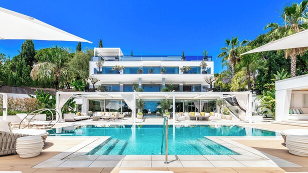 Un complexe hôtelier moderne doté d’une grande piscine, de chaises longues et d’un bâtiment à deux étages avec des balcons.