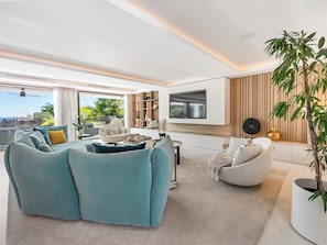 Una sala de estar moderna con un sofá modular, un televisor de pantalla plana y una gran planta en maceta.