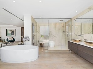 A modern bathroom with a large bathtub, a glass-enclosed shower, and a vanity with a marble countertop. - All About Villa Serenity (Marbella)