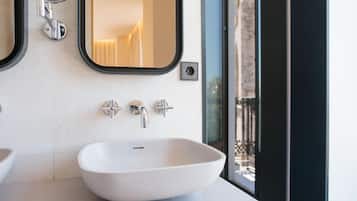 Un baño moderno con un lavamanos blanco, dos grifos cromados y un espejo encima.