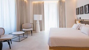 A modern hotel room with a large bed, a desk, and a chair. - MYR Puerta Serranos (Valencia)