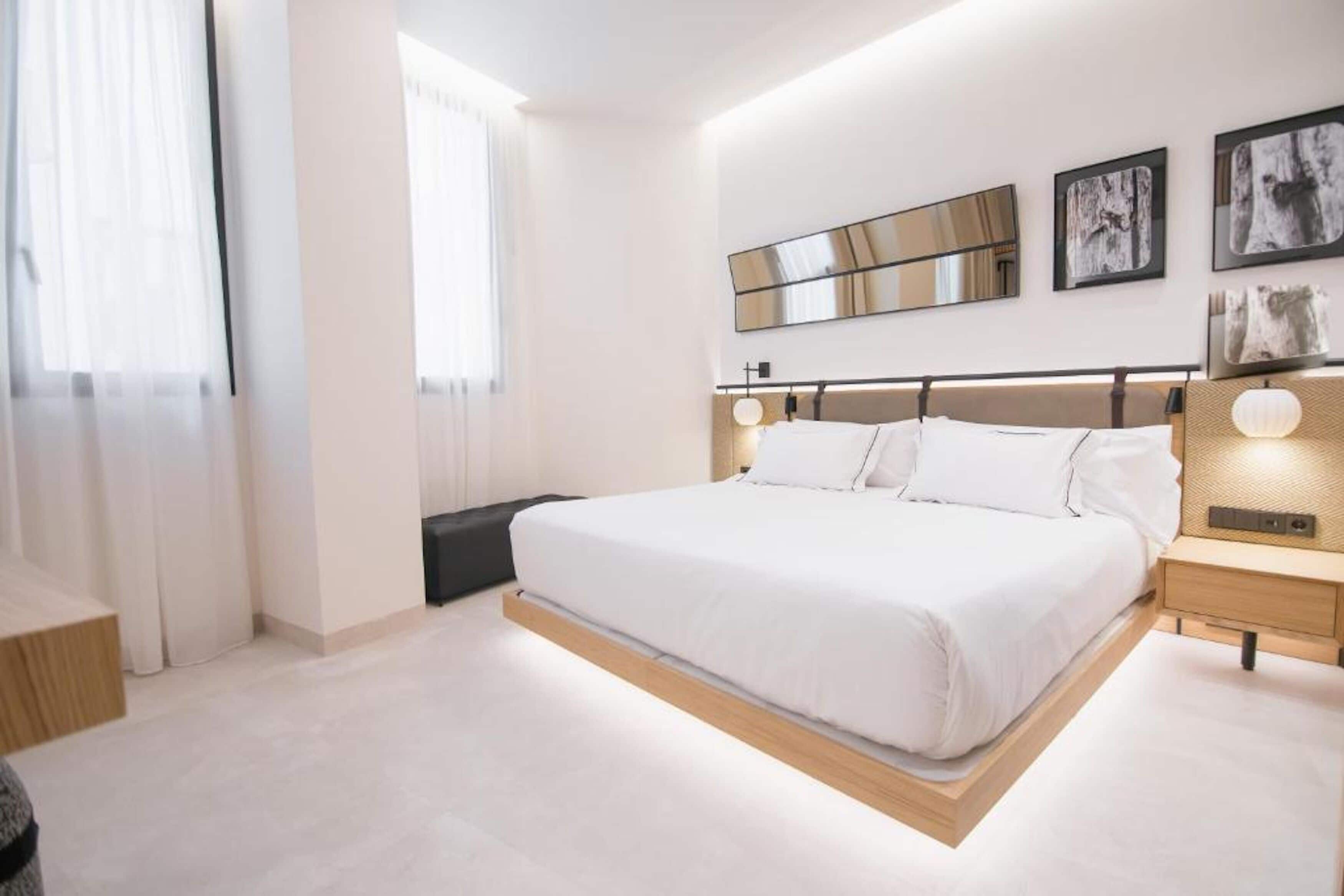Un dormitorio moderno con una cama grande, mesitas de noche y obras de arte en las paredes.