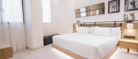 A modern bedroom with a large bed, bedside tables, and artwork on the walls.