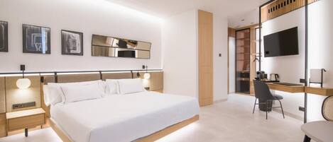A modern hotel room with a large bed, bedside tables, a desk, and a TV.
