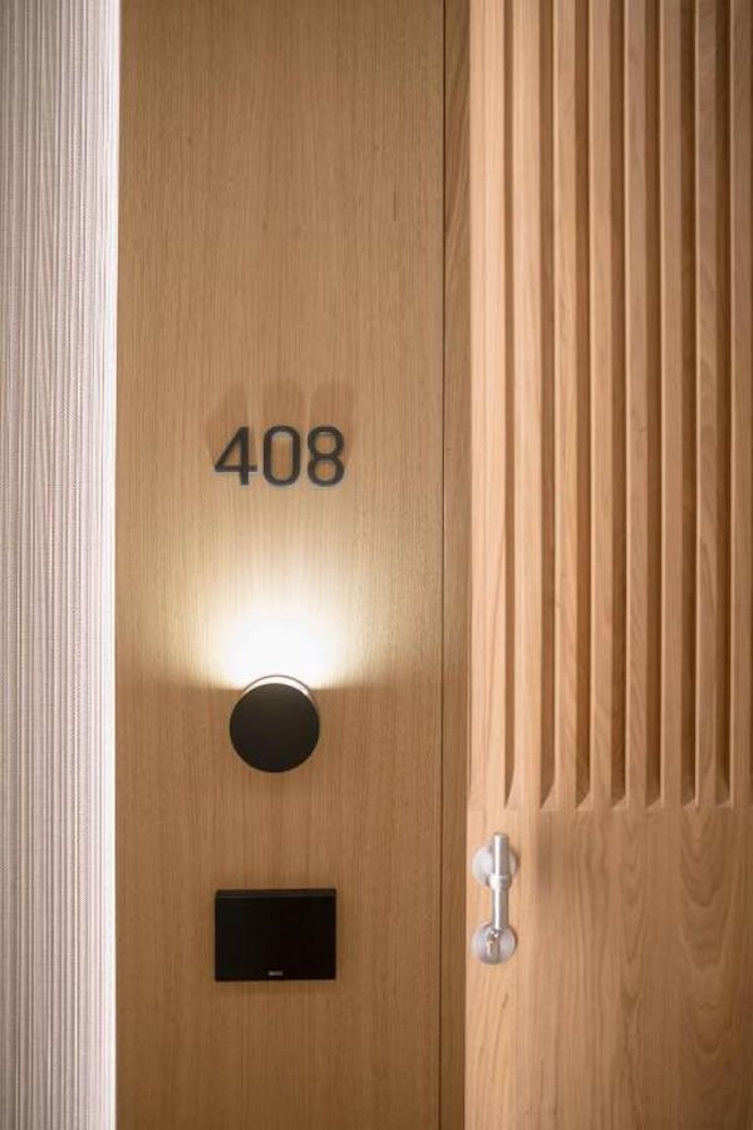 A wooden door with the number 408, a round light fixture, and a keyhole.