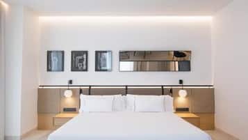 Un dormitorio moderno con una cama grande, mesitas de noche, un espejo montado en la pared y cuadros enmarcados.