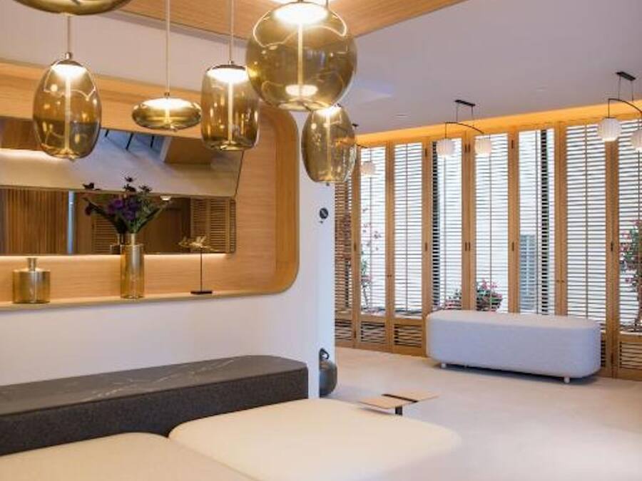 A modern interior with a seating area, pendant lighting, and a large window with blinds.