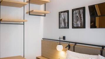 Une chambre d’hôtel moderne, équipée d’un lit, de tables de chevet et d’étagères intégrées.