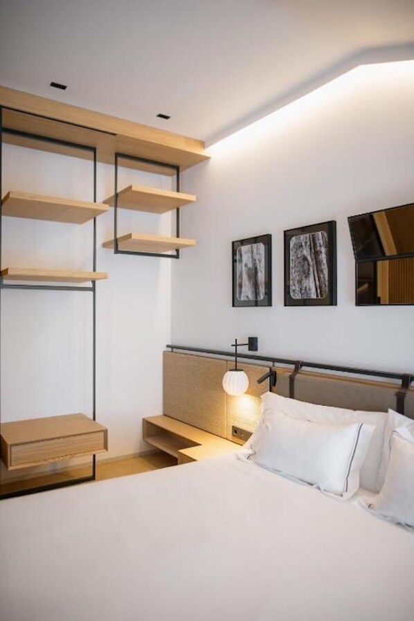 Una habitación de hotel moderna con una cama, mesitas de noche y estantes empotrados.