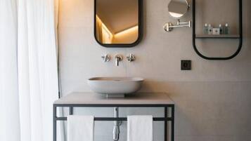 Un baño moderno con un lavamanos central, dos espejos y un perchero para toallas.