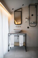 Un baño moderno con un lavamanos central, dos espejos y un perchero para toallas.