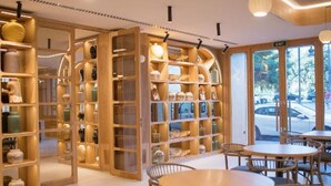 A modern interior with a round wooden table and chairs, surrounded by wooden shelving units with various items. - MYR Puerta Serranos (Valencia)