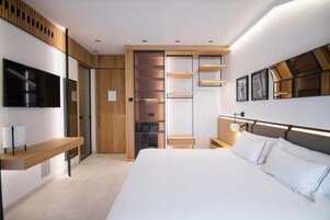 Une chambre à coucher moderne avec un grand lit, une armoire intégrée et un téléviseur fixé au mur.