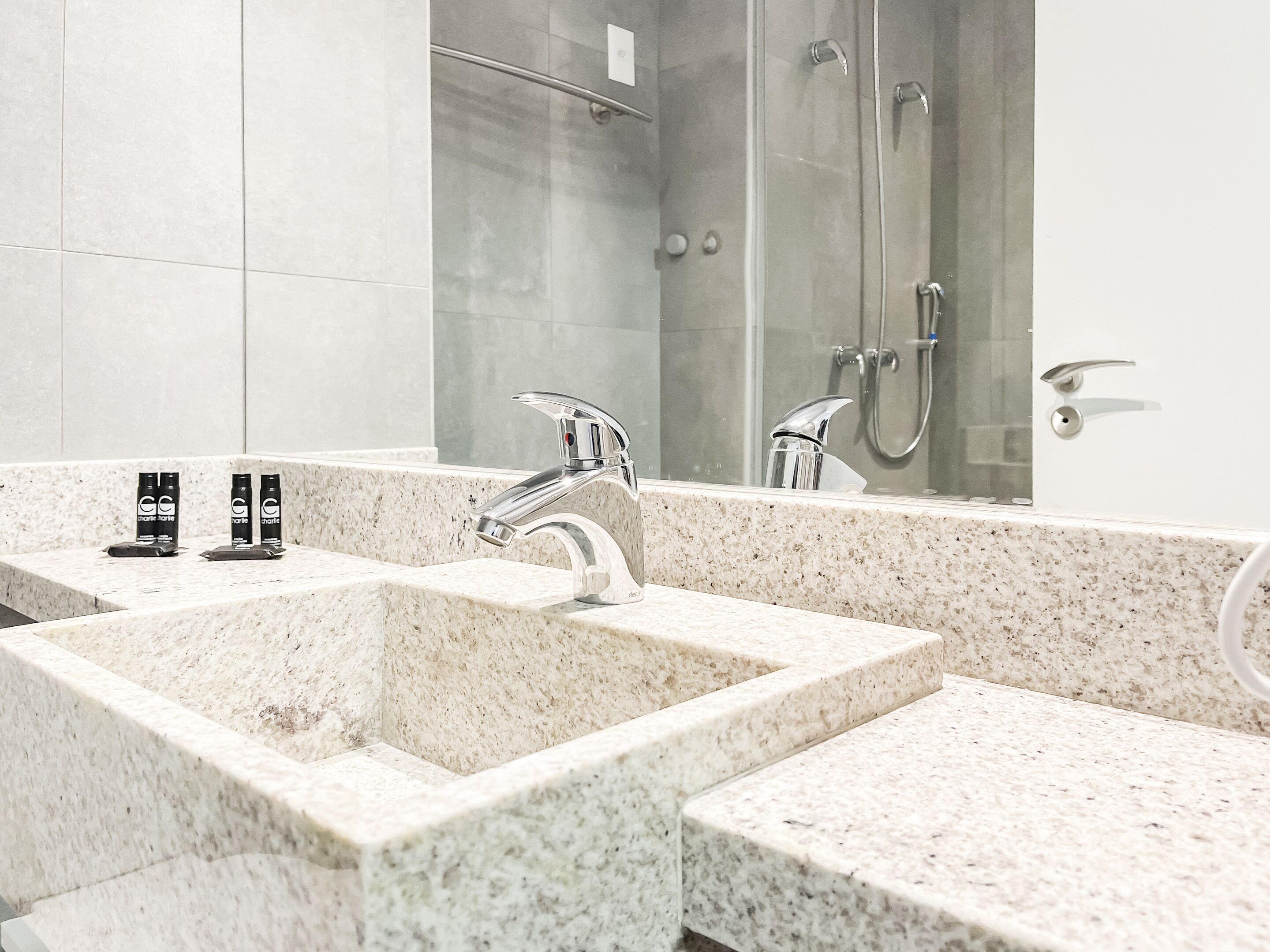 A bathroom with two sinks, a mirror, and a shower.