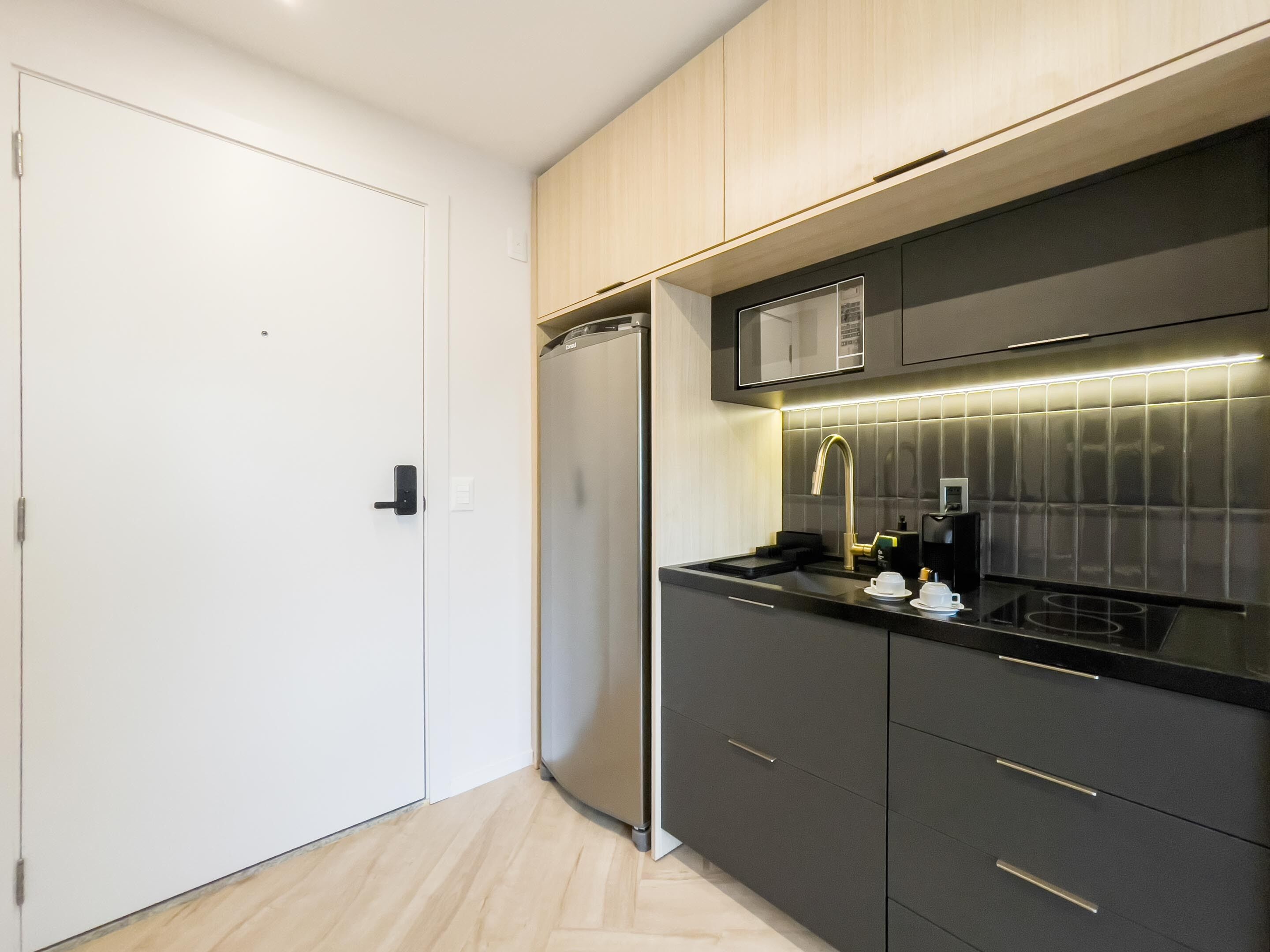 A modern kitchen with a built-in microwave, stainless steel appliances, and a sleek black countertop.