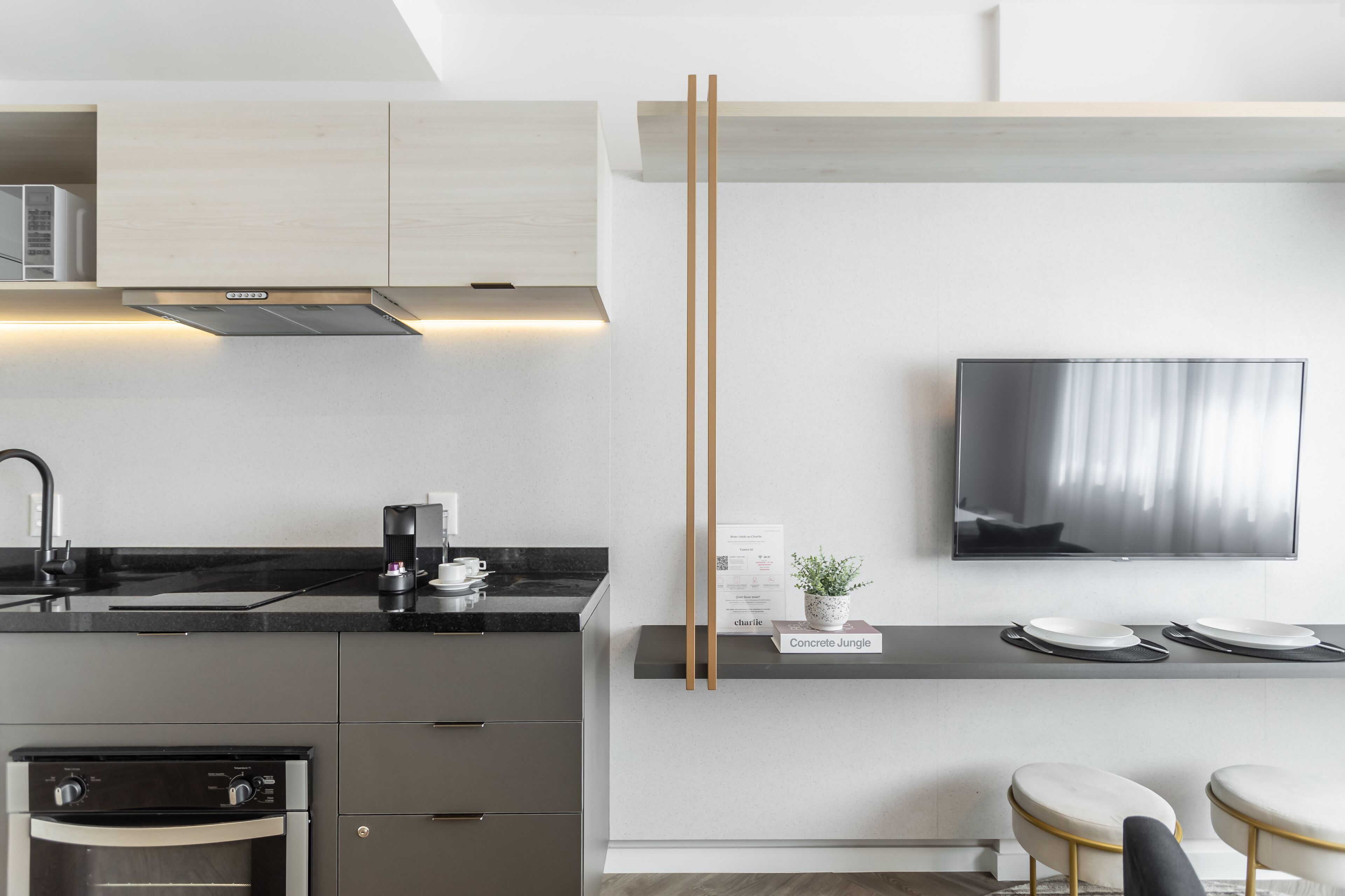 Eine moderne Küche mit Einbauofen, Kaffeemaschine und einem an der Wand befestigten Flachbildfernseher.