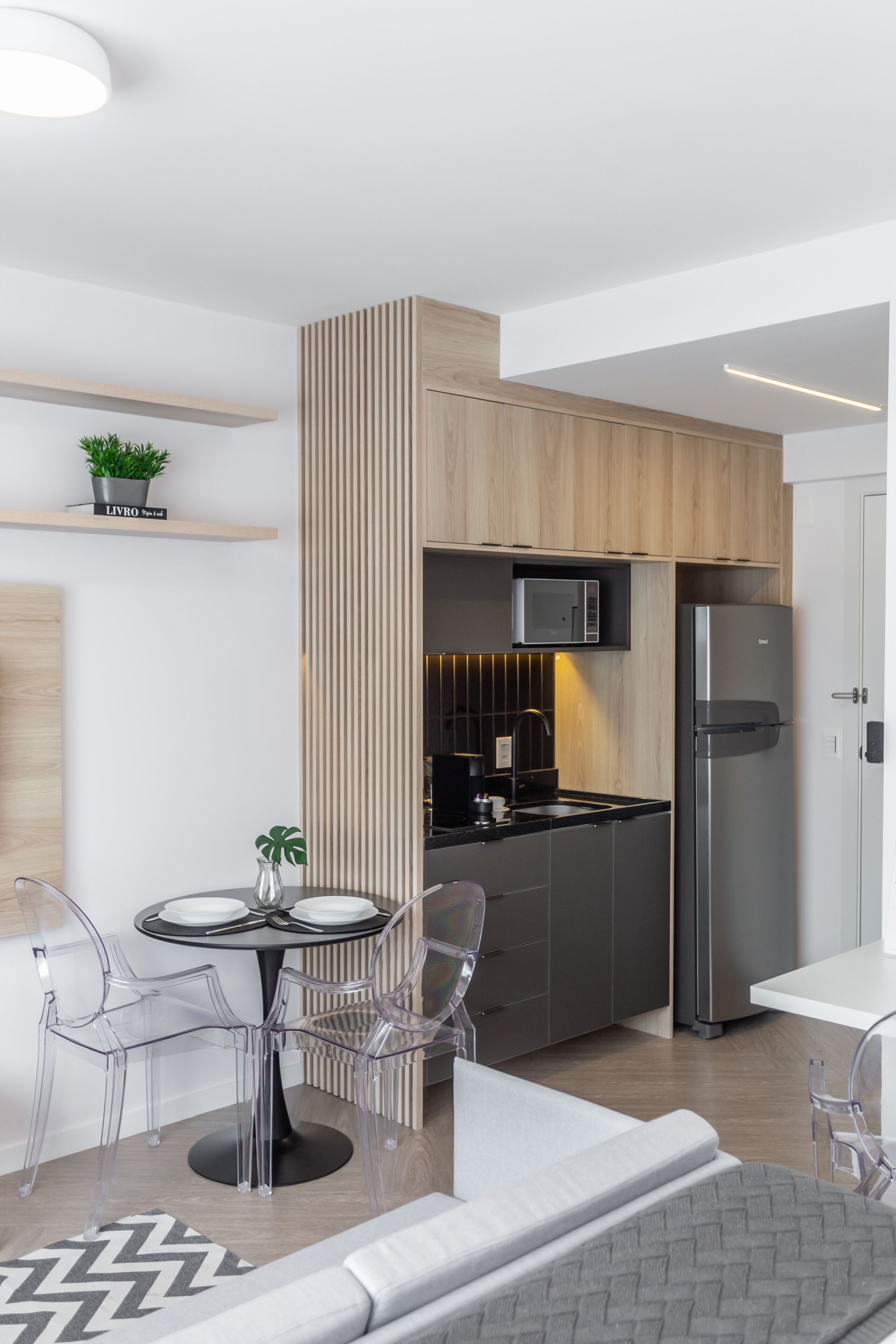 A modern kitchen with a built-in microwave, stainless steel refrigerator, and a wooden accent wall.