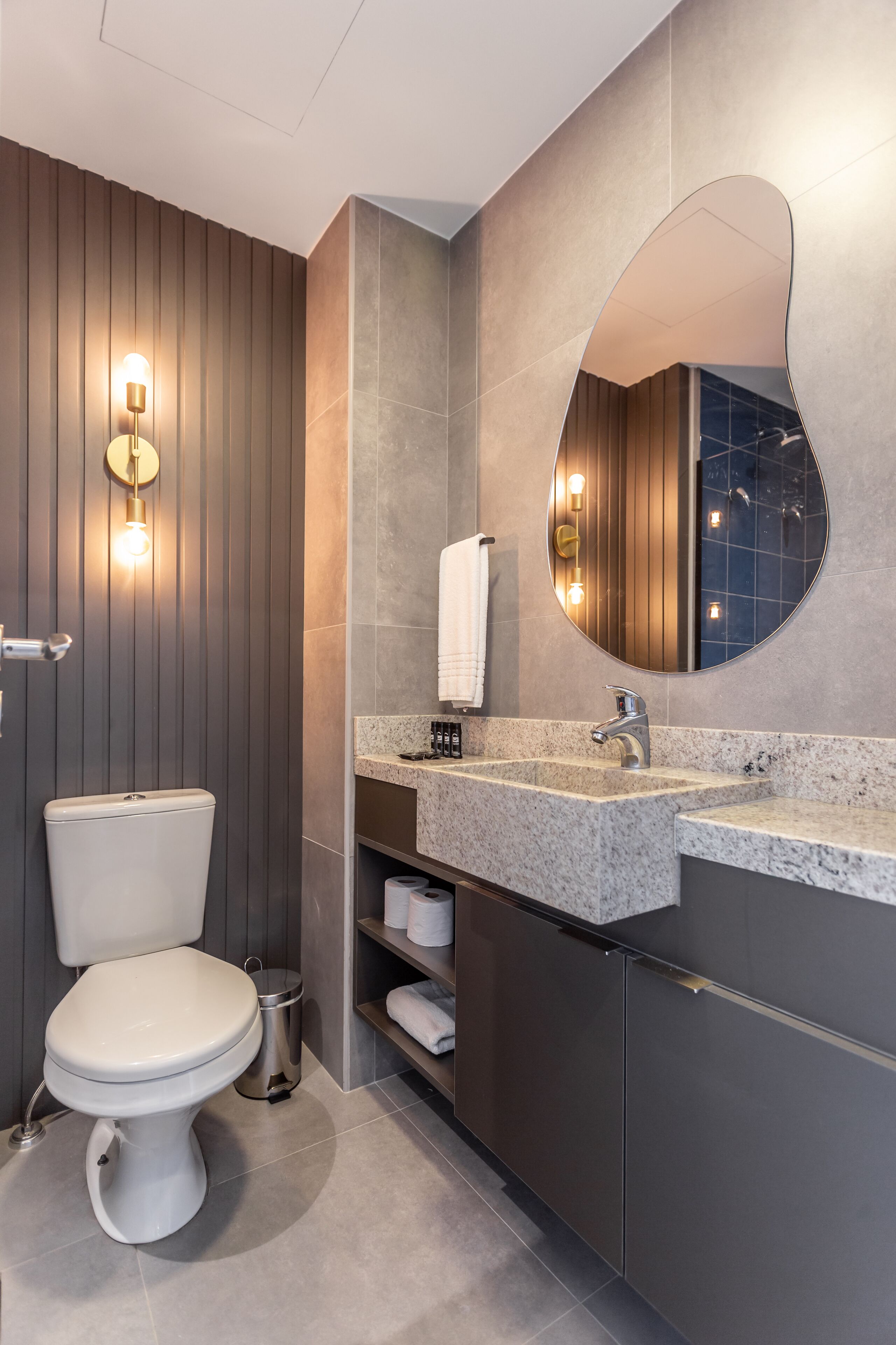 Un baño moderno con inodoro, tocador y un espejo grande.