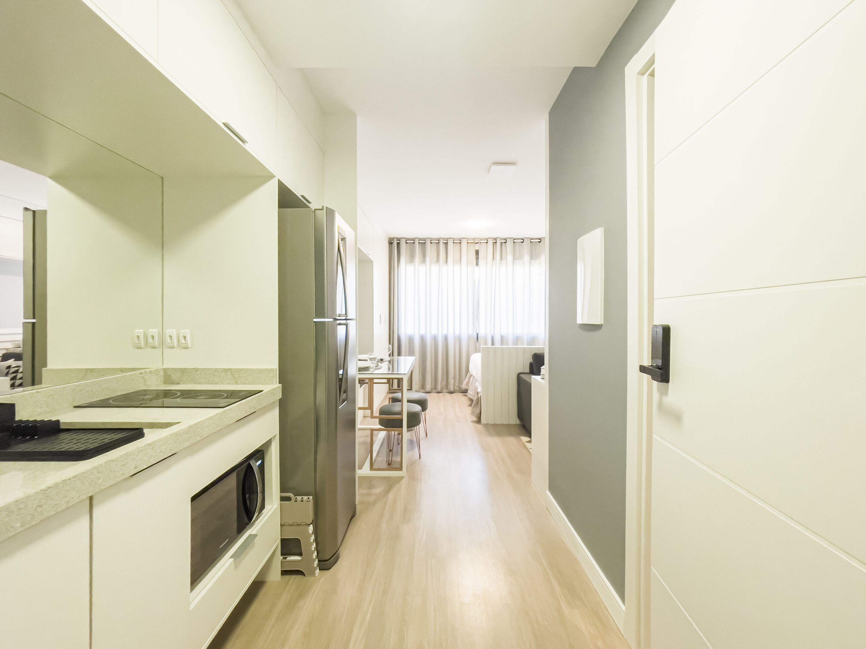A modern kitchen with a built-in oven, a refrigerator, and a dining area with a table and chairs.