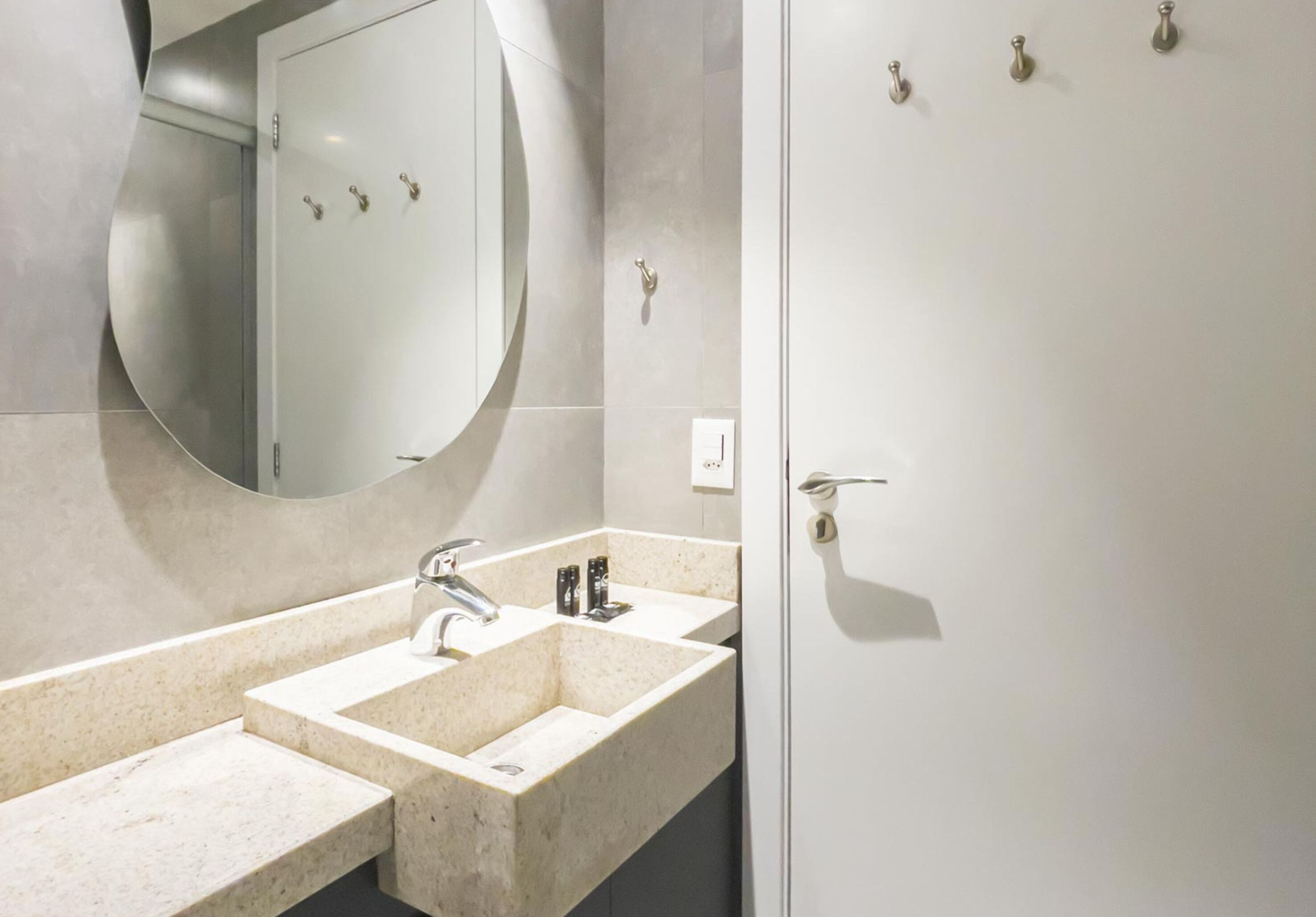 A modern bathroom with a double sink, a large mirror, and a door with a handle.