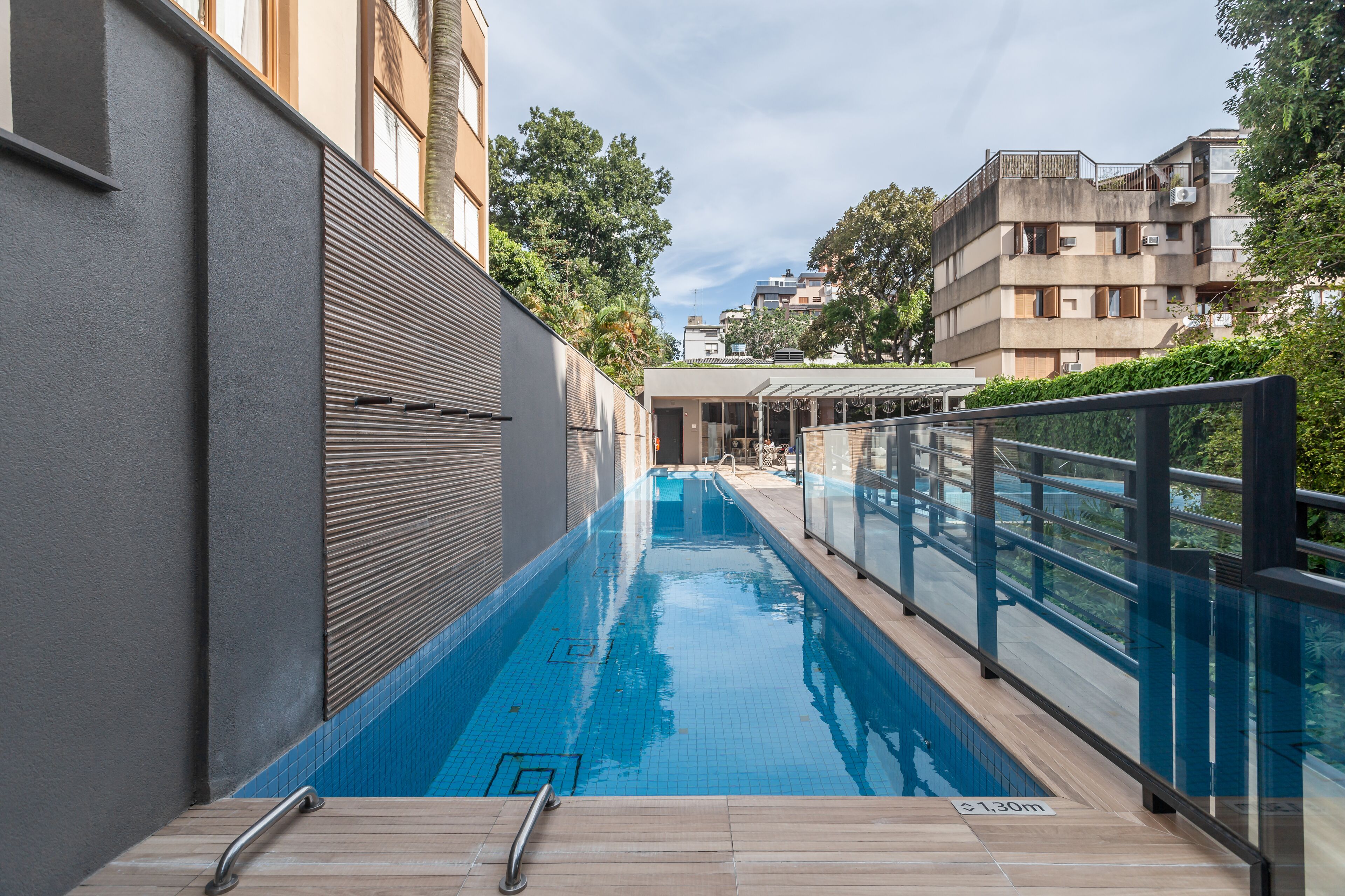 A swimming pool with a glass barrier, a metal handrail, and a sign indicating a depth of 1.30m.