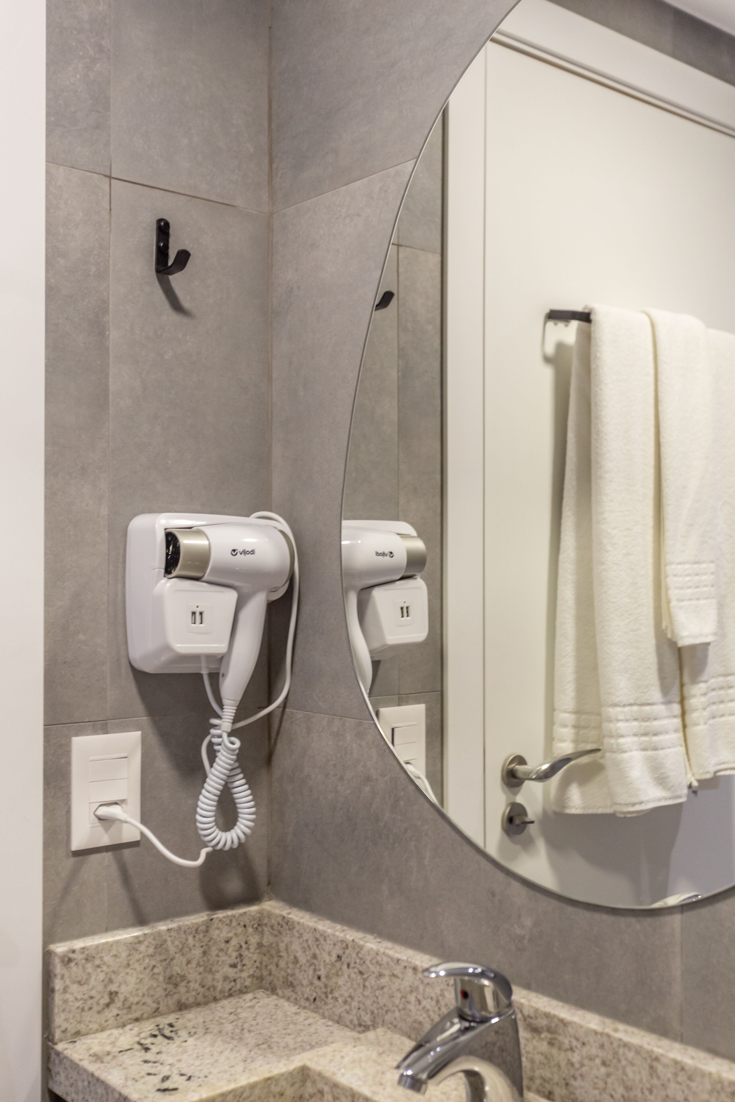 Ein Badezimmer mit Spiegel, Fön und Handtuchhalter.