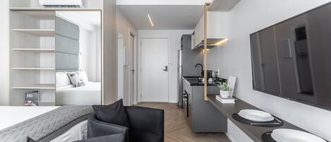 Een moderne, compacte leefruimte met een kitchenette, een eethoek en een slaapkamer.
