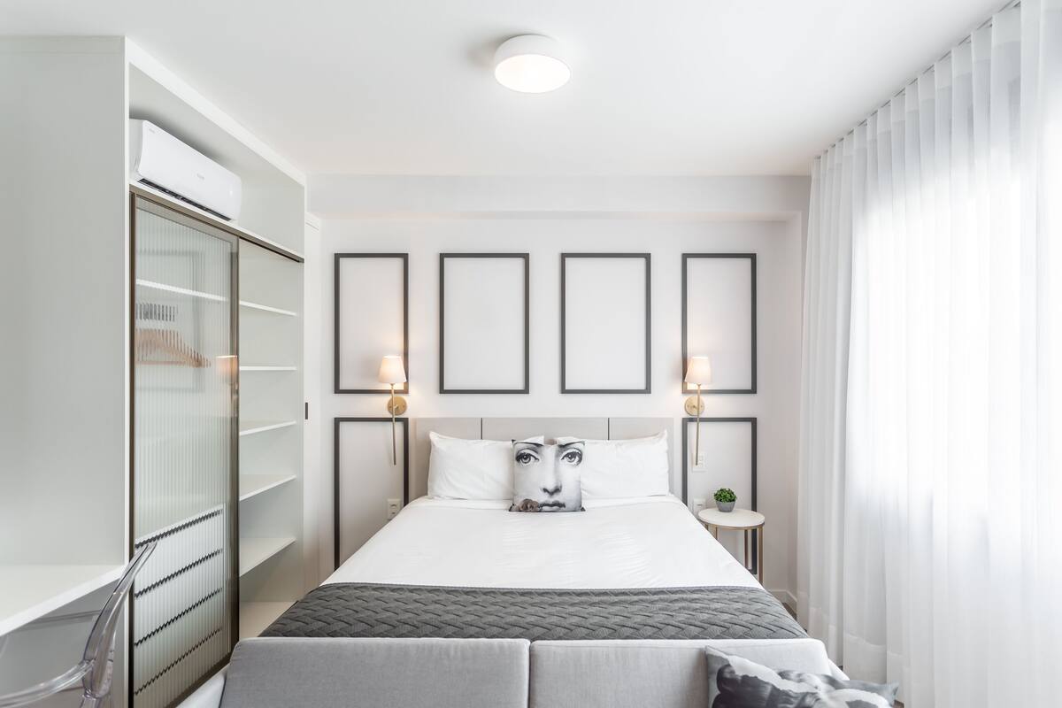 A modern hotel room with a bed, bedside tables, a wardrobe, and framed pictures on the wall.