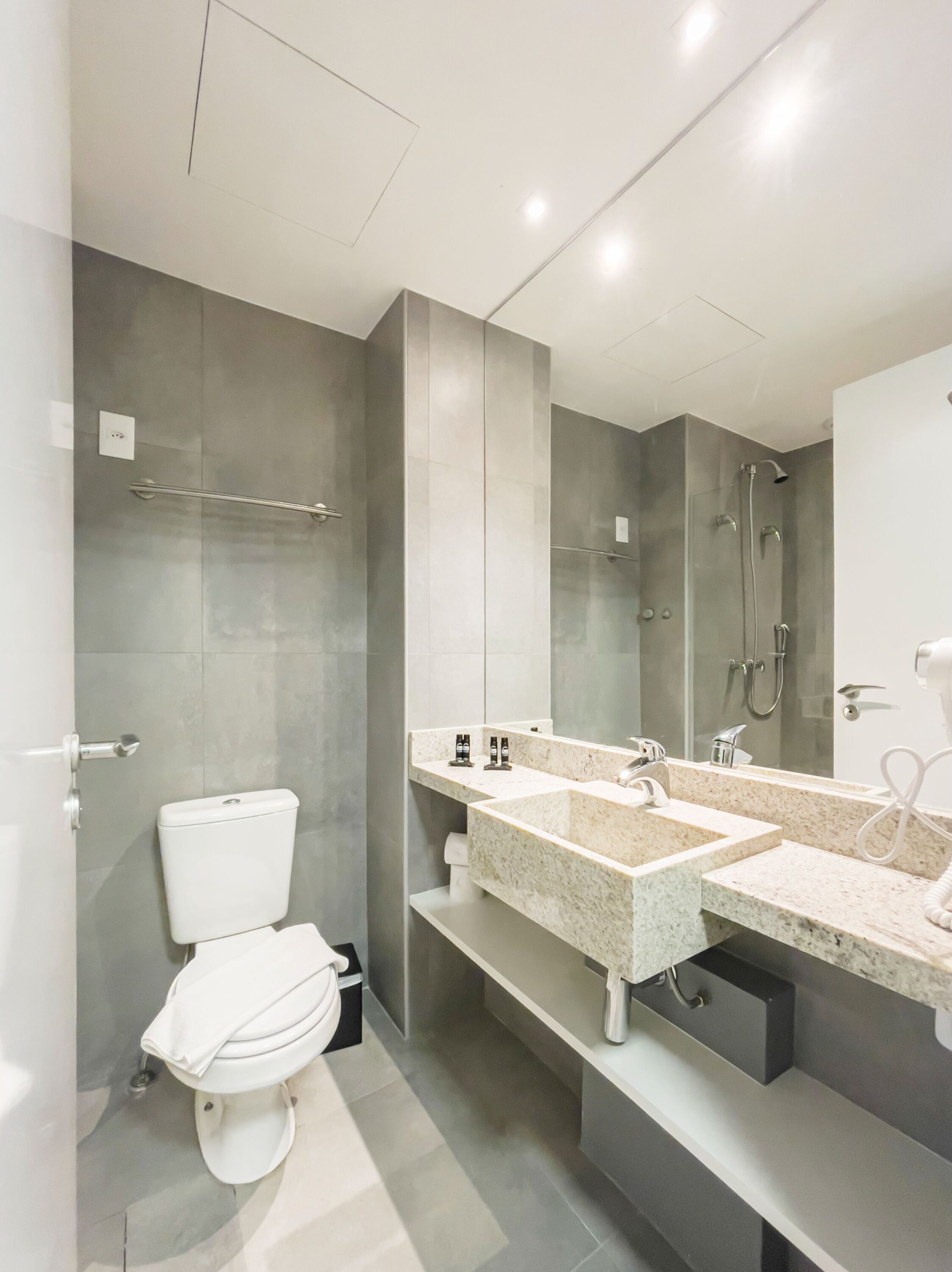 A modern bathroom with a toilet, a sink with a mirror, and a shower area.