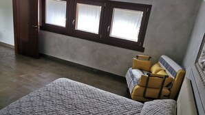 Une chambre à coucher avec un lit, un canapé, une fenêtre et un radiateur.