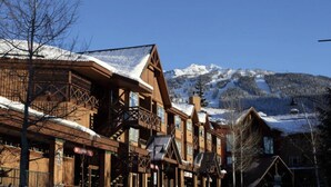 A wooden building with balconies and a snow-covered mountain in the background. - Whistler Village 1BR: Sleeps 4,Walk to Everything & Free Parking! (Whistler)