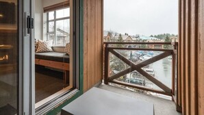 A balcony with a view of a river and buildings, a wooden interior, and a bed with pillows. - Whistler Village 1BR: Sleeps 4,Walk to Everything & Free Parking! (Whistler)
