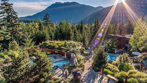 A resort with multiple swimming pools surrounded by lush greenery and mountains in the background. - Whistler Village 1BR: Sleeps 4,Walk to Everything & Free Parking! (Whistler)