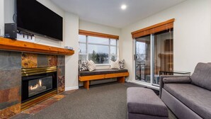 A living room with a fireplace, a television, a bench, and a sofa. - Whistler Village 1BR: Sleeps 4,Walk to Everything & Free Parking! (Whistler)
