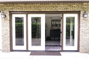 Entrada de edifício com fachada de tijolos e grandes portas de vidro que dão para uma garagem.