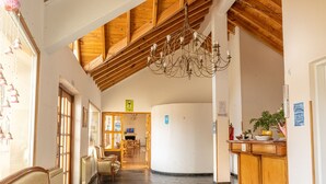 Vestíbulo de hotel con techo de madera alto, un candelabro, una recepción y zonas de estar.