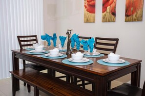 A dining table set with white bowls, plates, and glasses, blue napkins, and a decorative vase. - 5156 Amazing Townhome 4bd/3.5bth Near Disney Parks  (Kissimmee)
