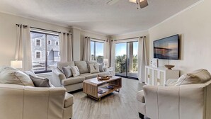 A spacious living room with a sofa set, a coffee table, and a TV mounted on the wall. - Oceanfront Balcony Views, Pool, STEPS to Beach Restaurants Shops (Wrightsville Beach)