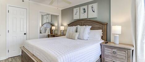 A bedroom with a bed, a nightstand, a ceiling fan, and wall art.