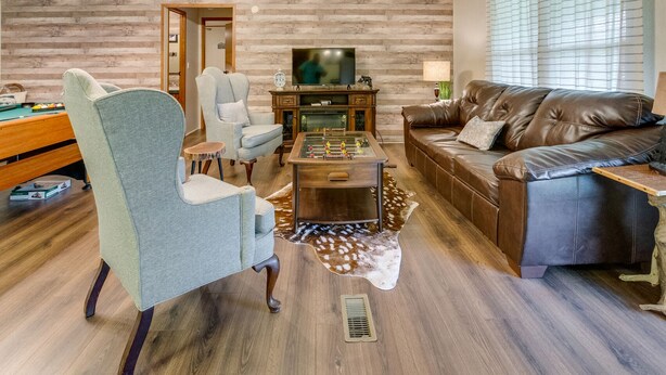 Een gezellige woonkamer met een houten wand, een leren bank, een salontafel en een televisie.