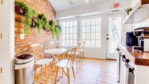 A modern kitchen with a brick wall, wooden flooring, and a coffee machine.