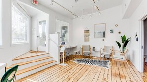 A modern interior with wooden flooring, a staircase, a desk, chairs, and a zebra print rug.