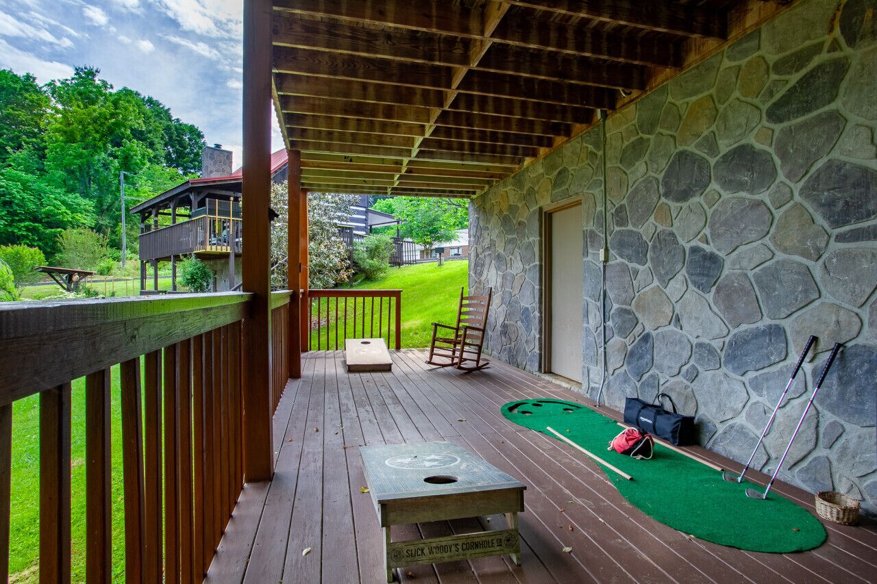 Une terrasse couverte avec un green d’entraînement, un mur en pierre et une rambarde en bois.